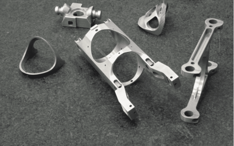 Five machined metal aerospace components with precision features
