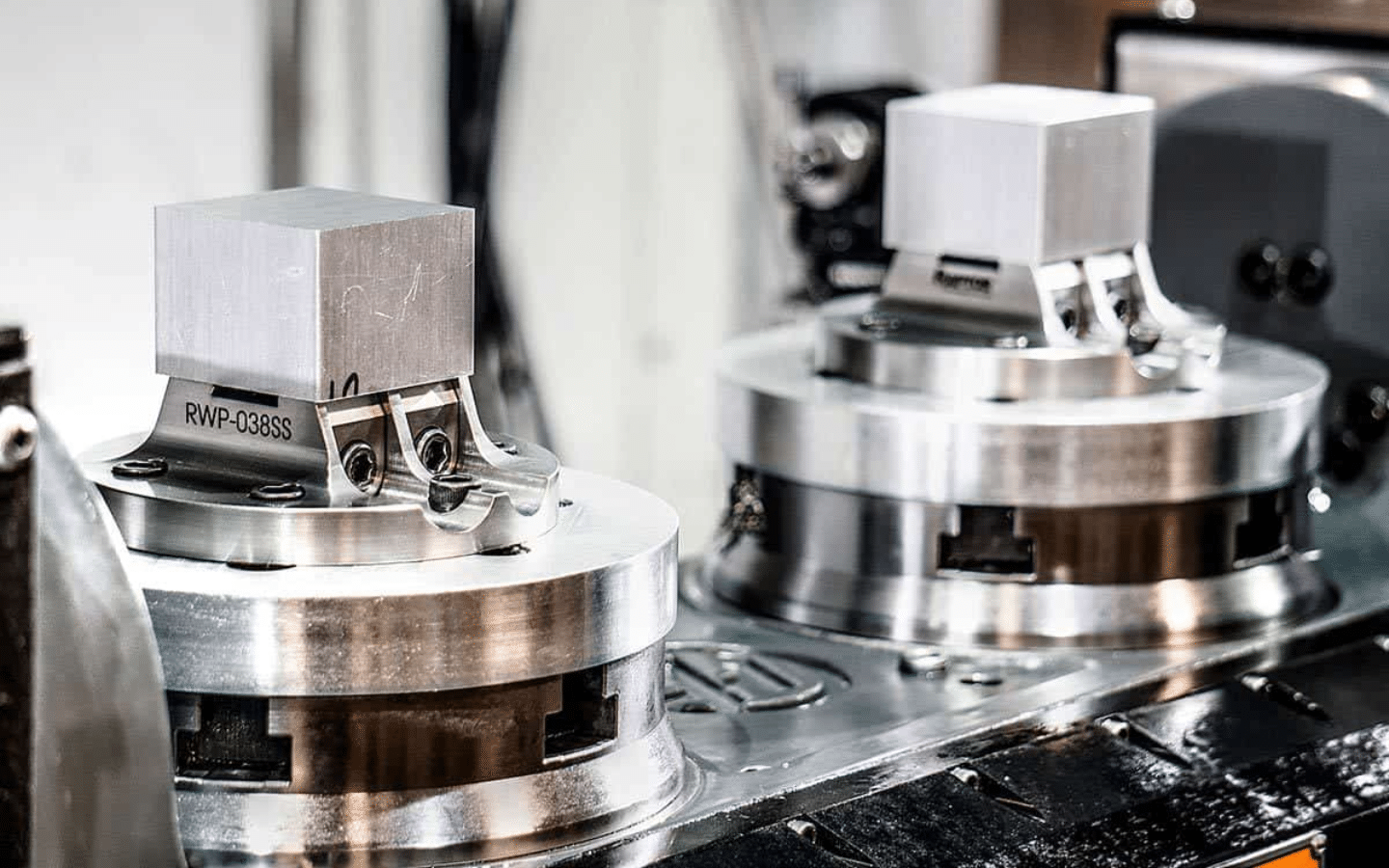 two metallic CNC prototypes on circular bases in a workshop setting