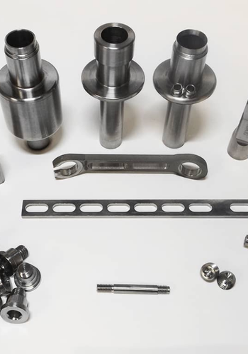 Precision-engineered metal parts including cylinders, brackets, and screws on a white background