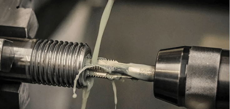 Metal threading tool cutting screw threads with coolant