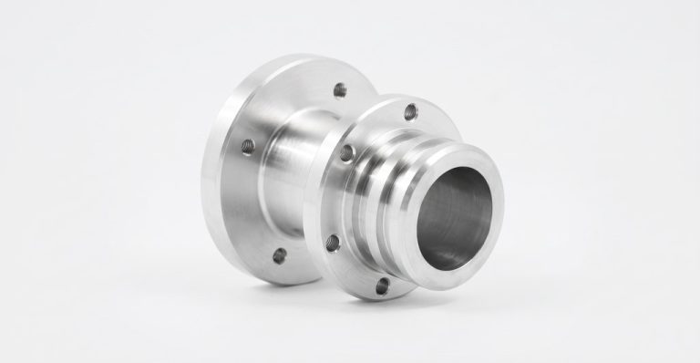 Precision machined metal fitting with flange and bore