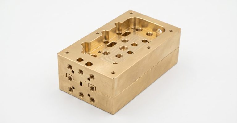 Brass aerospace housing with machined cavities and threaded holes
