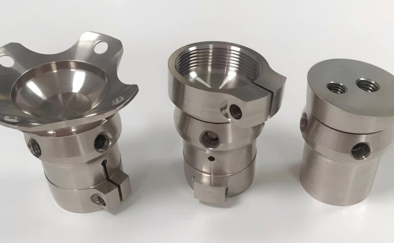 Three precision machined titanium aerospace components with threaded features