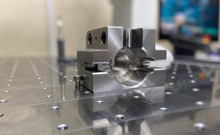 Machined metal component with threaded bore on precision table