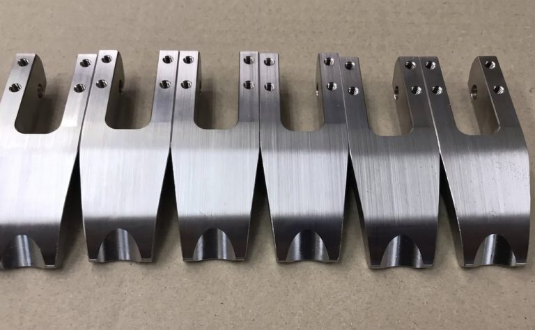 Six machined metal brackets with brushed finish and mounting holes
