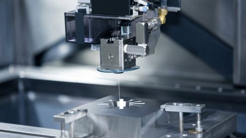 Wire cut EDM machine cutting precision metal part on fixture