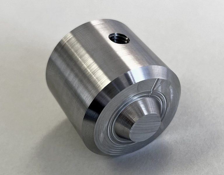 Cylindrical machined metal part with hole and stepped features