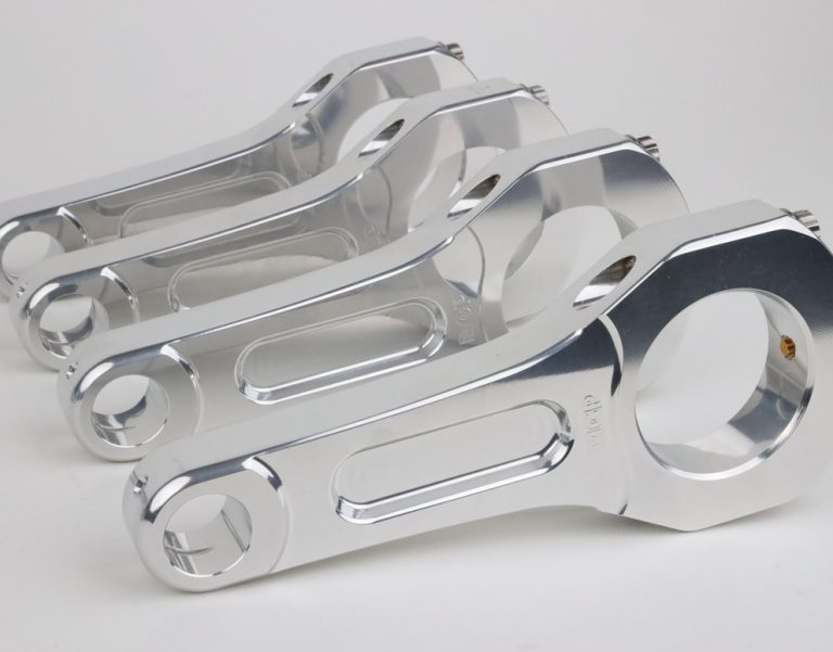 Four polished aluminum connecting rods on white