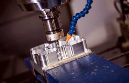 CNC milling cutter machining an aluminum part clamped in a vise