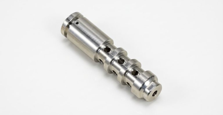 CNC machined metal cylinder with holes and grooves