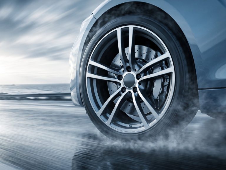 Automotive industry: a sleek unbadged modern electric saloon car driving fast on a coastal highway at dawn