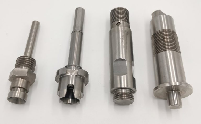 Four precision machined metal automotive parts with threaded features