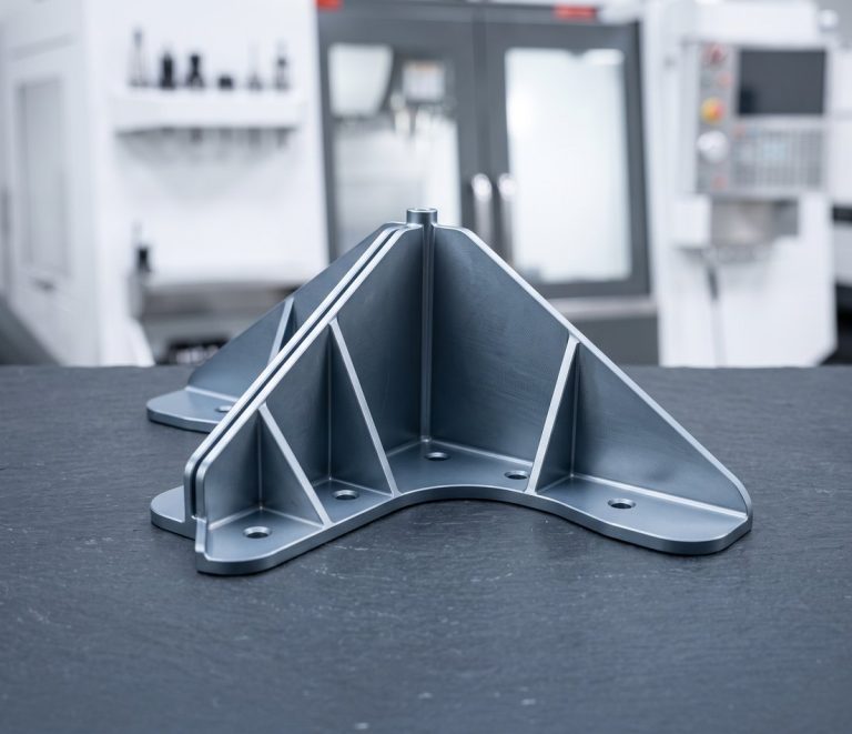 Custom machined aluminum angle bracket on dark worktable