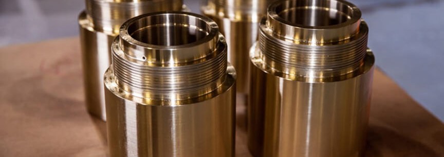 Four machined bronze cylindrical parts on wooden surface