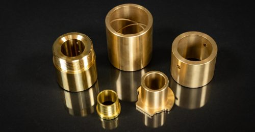 Bronze machined bushings and sleeves on black surface