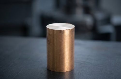 Raw bronze 954 round bar stock on dark table