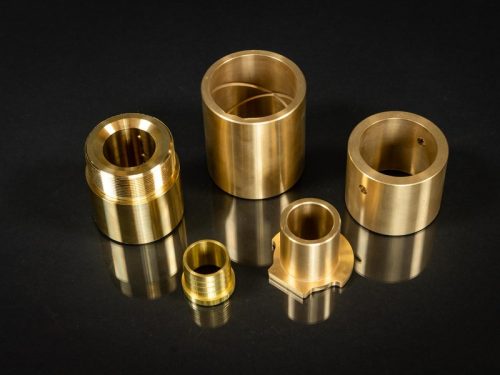 Bronze machined bushings and sleeves on black surface
