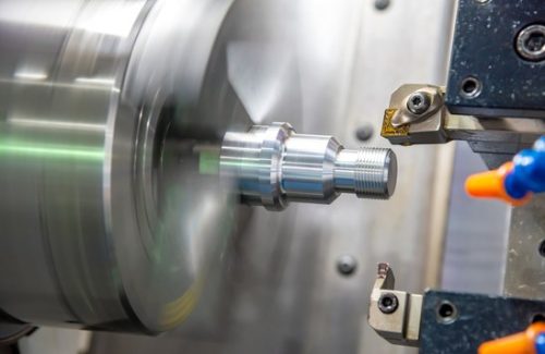 CNC lathe turning a stepped steel shaft
