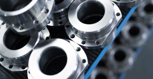 Stacked machined metal flanges on blue tray