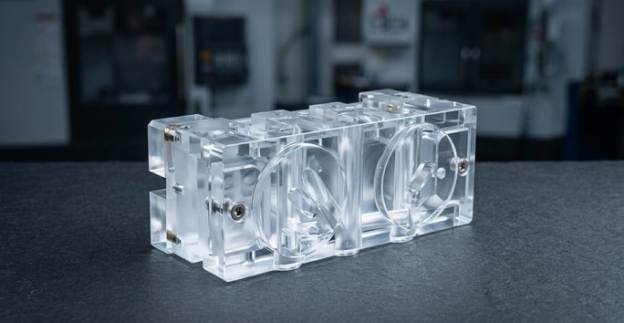 CNC machining plastics clear PMMA manifold on worktable