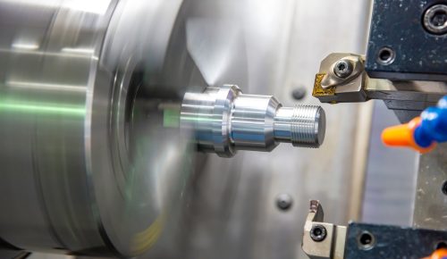 Knurled steel shaft being CNC turned on a lathe chuck