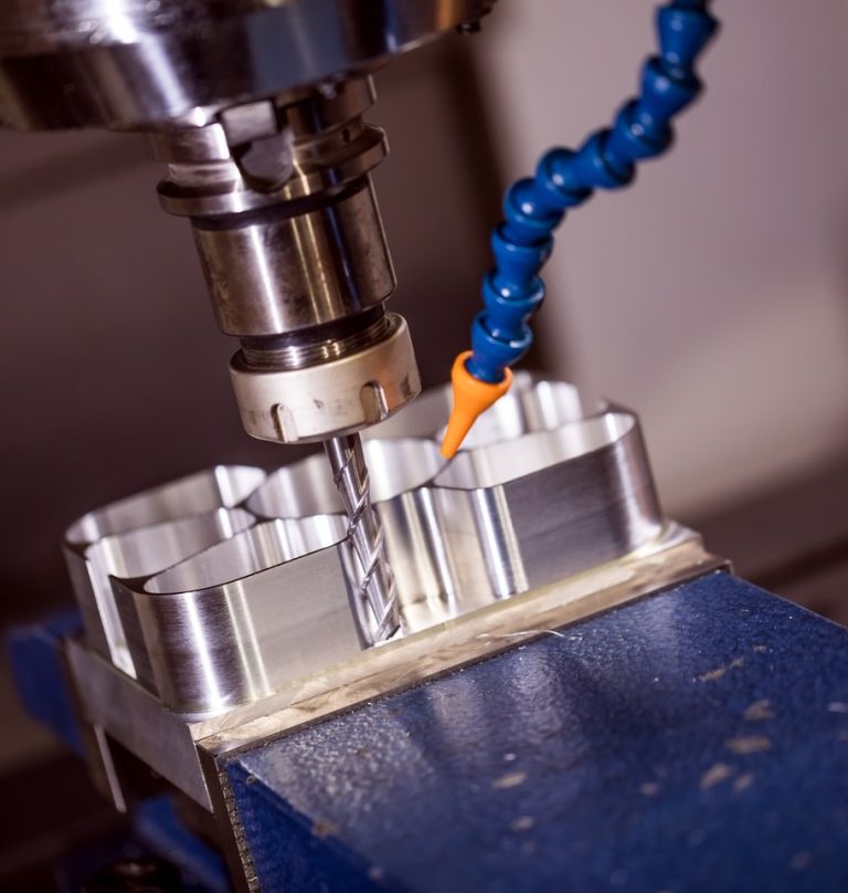 CNC milling cutter machining an aluminum part clamped in a vise