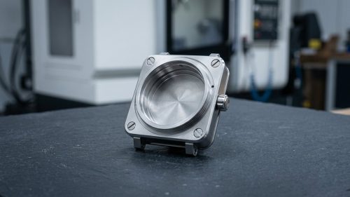 Custom watch parts stainless steel case machined on dark worktable
