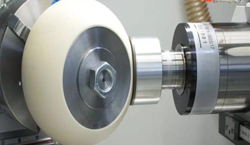 Cylindrical grinding wheel finishing a steel shaft on CNC grinder