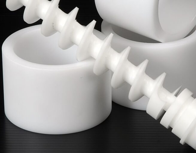 White acetal plastic machined parts on black surface
