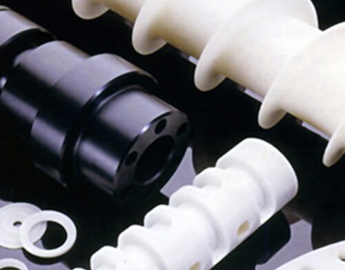 White plastic and black metal machined parts on dark surface