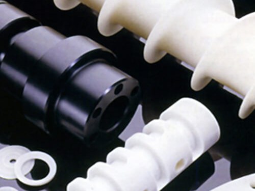 White plastic and black metal machined parts on dark surface
