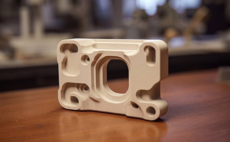 CNC machined beige PEEK component with precision holes