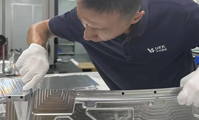DEK inspector checking a machined aluminum plate