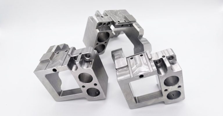 Three machined aluminum brackets with precision holes and slots