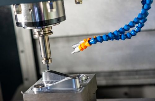 CNC milling of an aluminum part in a vise with coolant spray