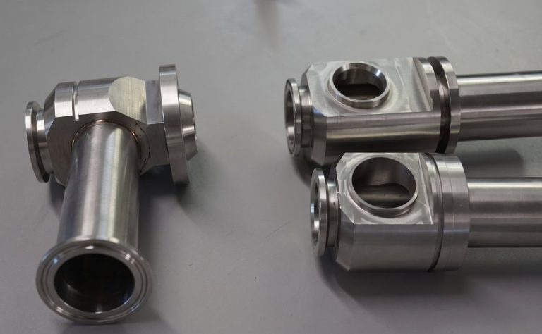 Hand holding machined steel marine parts on gray surface