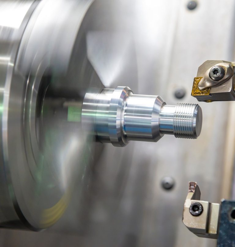 CNC lathe turning a stepped steel shaft