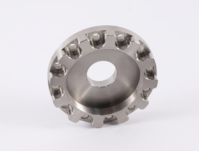 Circular machined metal part with teeth and central hole