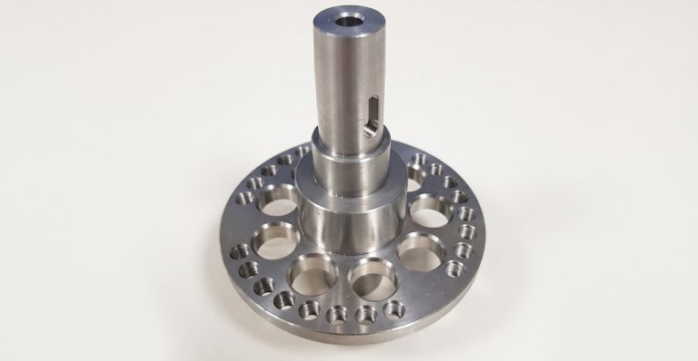 Precision machined metal flange with central shaft and holes