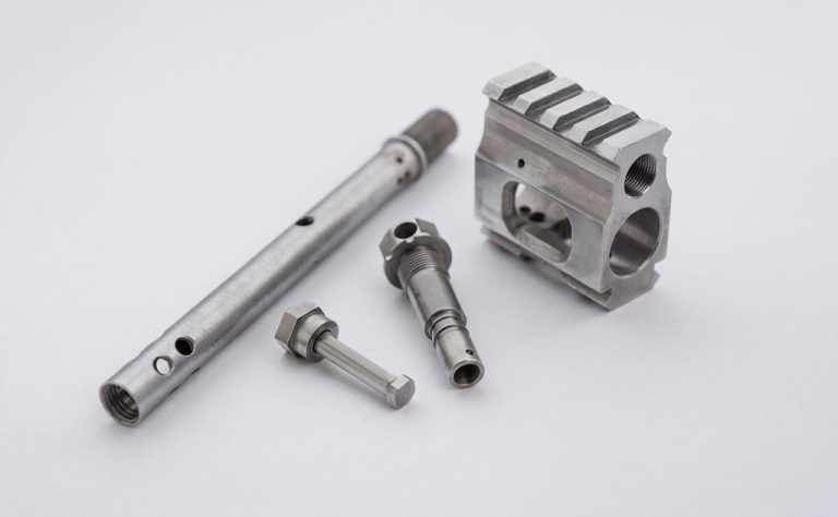 Four precision machined metal parts with threaded features