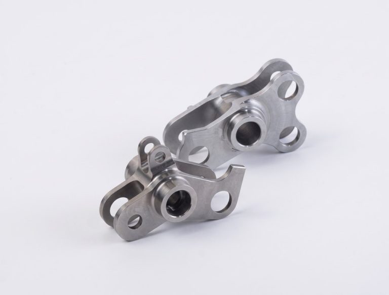 Two machined metal brackets with holes and threaded inserts