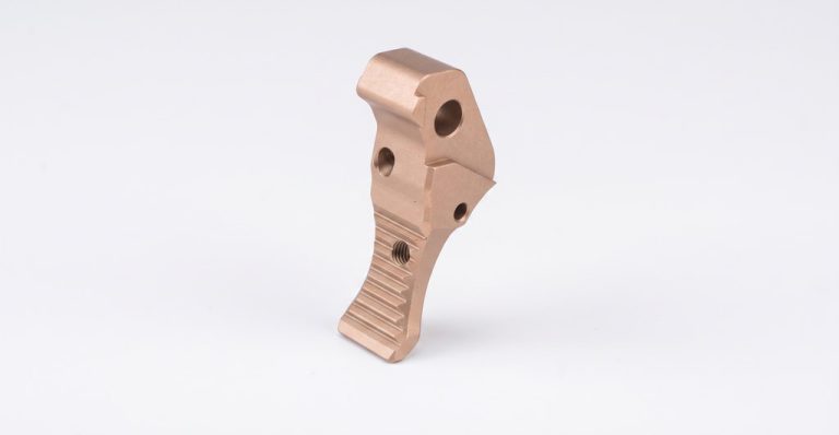 Machined metal trigger component with textured grip surface