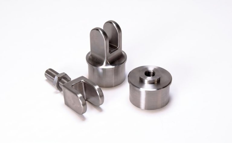 Three precision machined titanium parts with threaded features