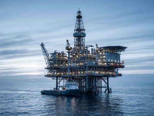 Oil & Gas industry: an offshore oil and gas production platform standing in a calm sea at dusk