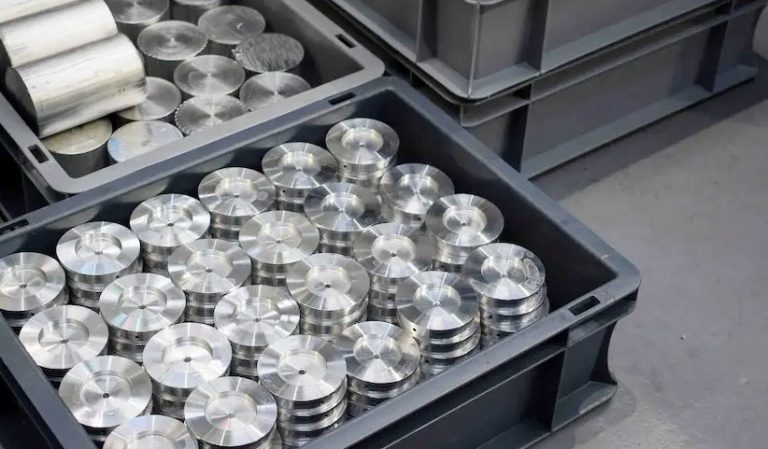 Turned aluminum spacers stacked in black plastic crates for delivery