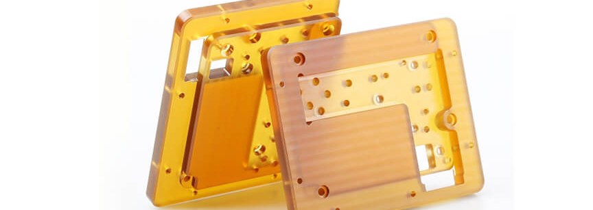 Two amber PEI plastic machined enclosures on white