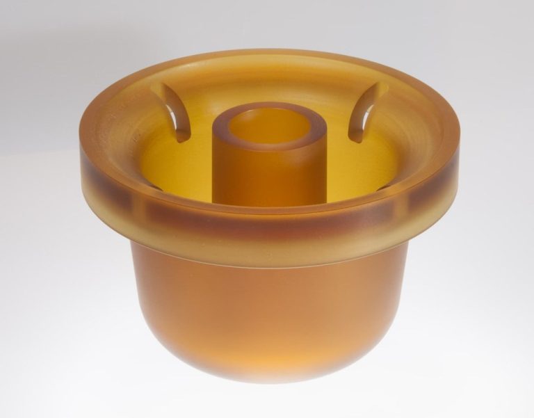 Amber translucent machined plastic part on white
