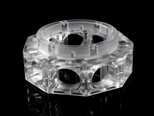 Transparent polycarbonate machined part on black background