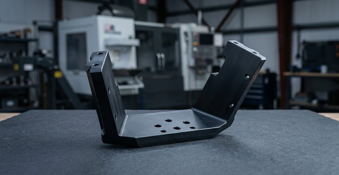 Black POM Delrin bracket component on dark worktable