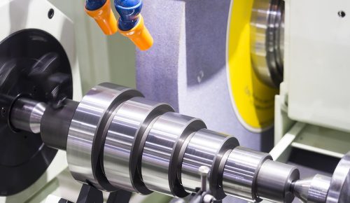 Cylindrical grinding wheel finishing a hardened steel shaft on CNC grinder